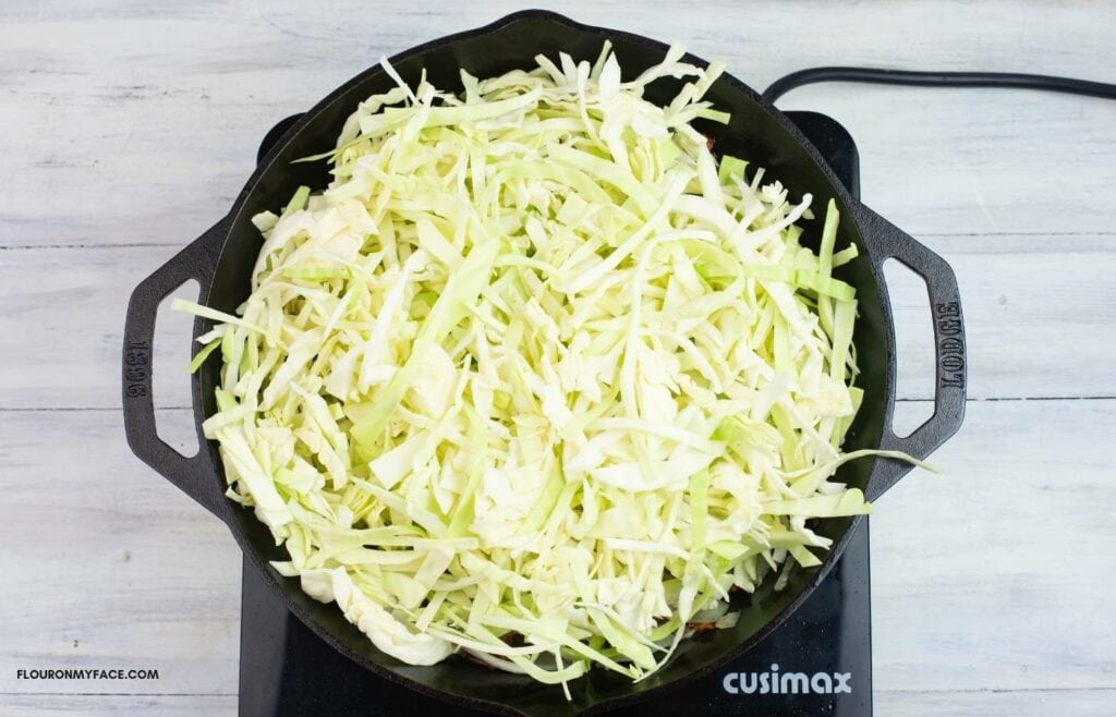 Cooking sliced cabbage in an iron skillet.