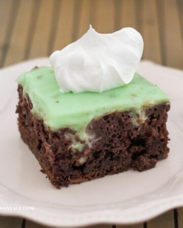 Pistachio Poke Cake on a plate topped with whipped cream.