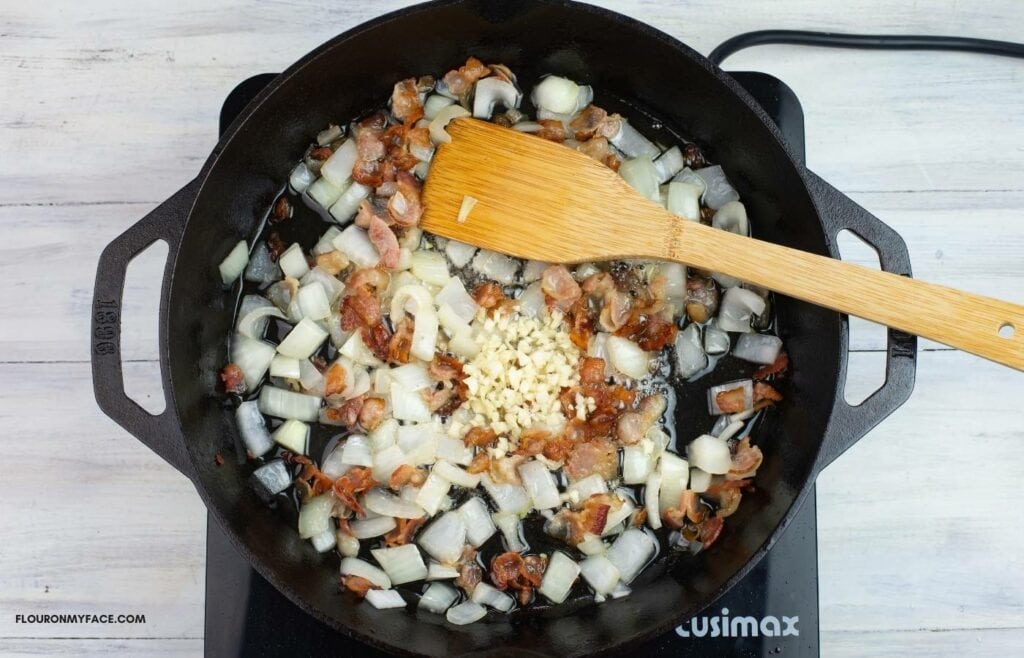 Cooking bacon, onion and minced garlic in a iron skillet.