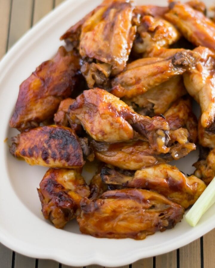 A serving platter with a stack of honey bbq buffalo chicken wings.