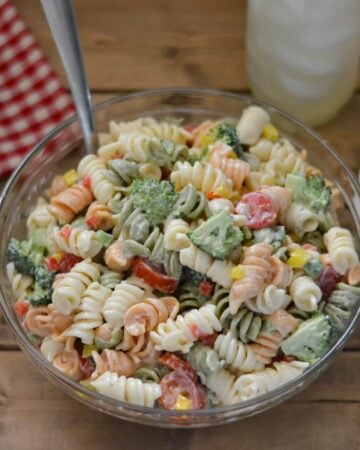 Glass bowl filled with broccoli and tomato pasta salad.