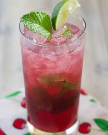 Cherry Mojito in a tall glass garnished with lime and mint.