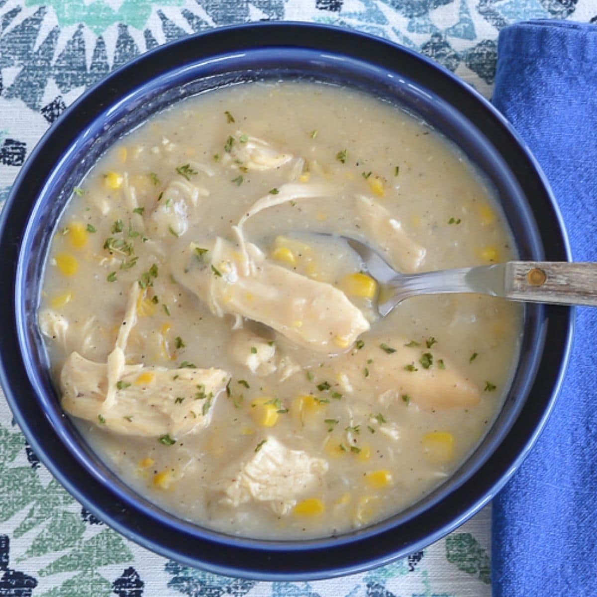 Chicken corn chowder served in a blue bowl on a placemat.