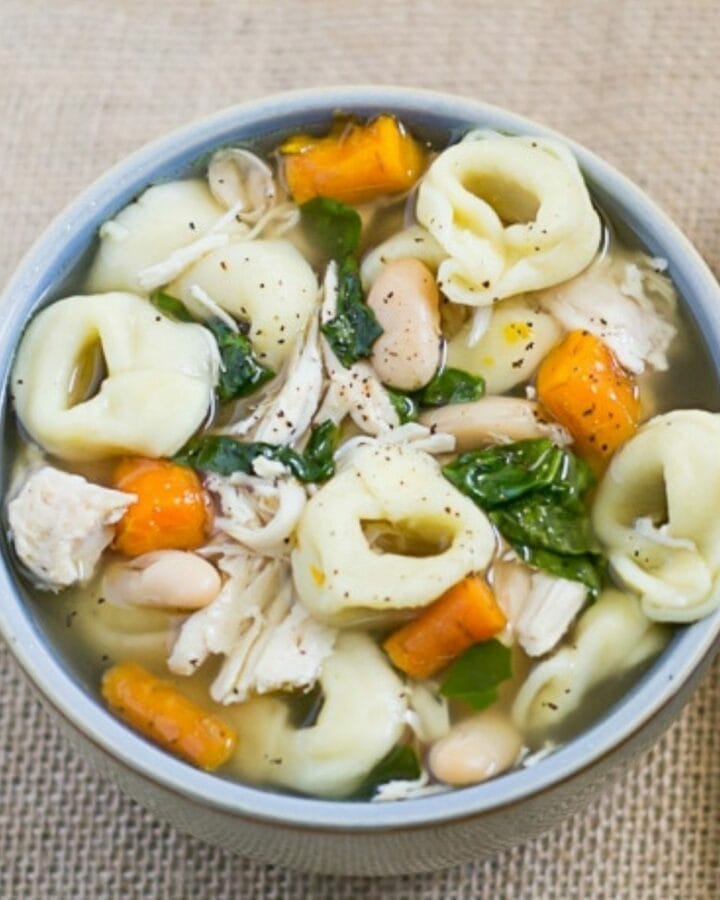 A soup bowl filled with chicken tortellini soup.