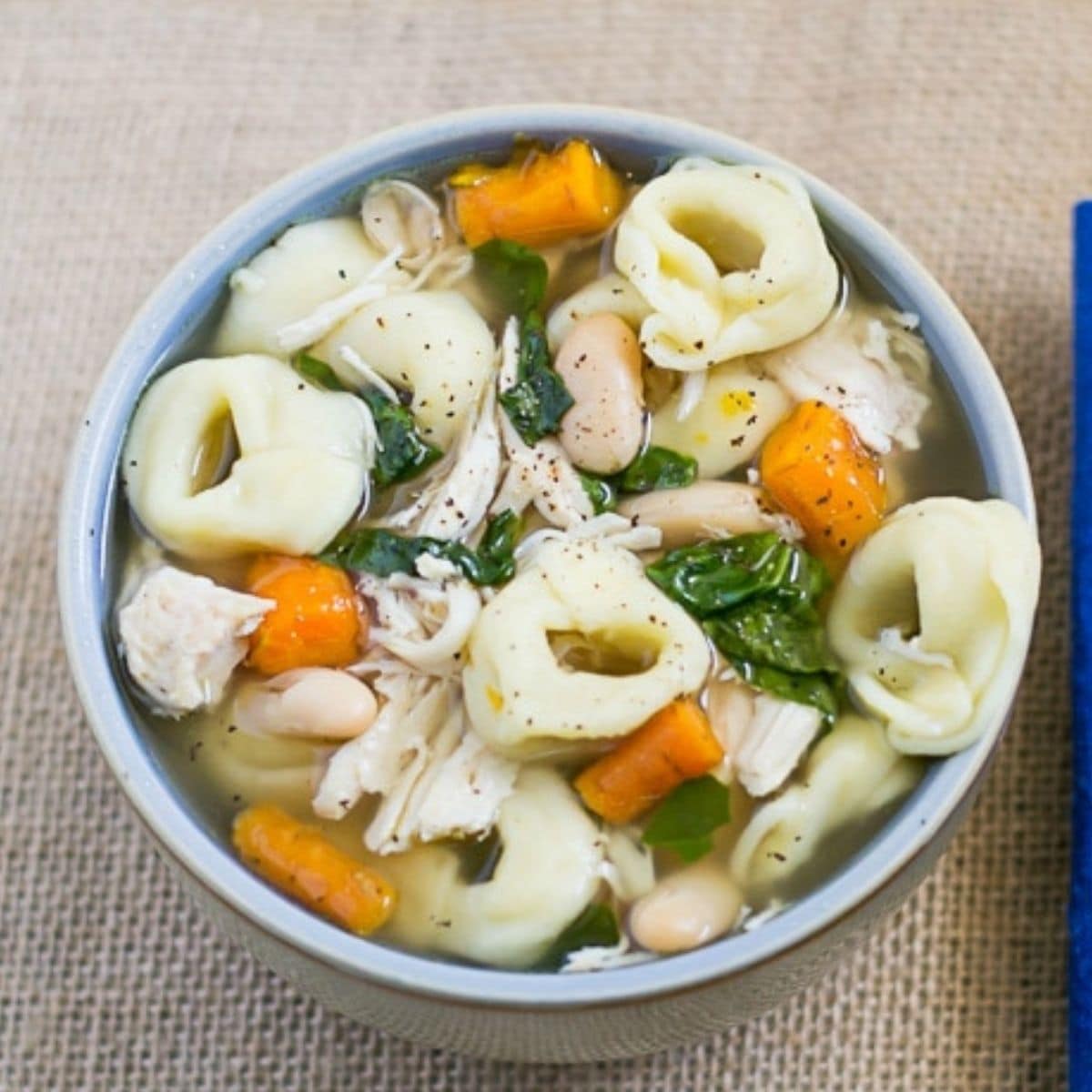 A soup bowl filled with chicken tortellini soup.