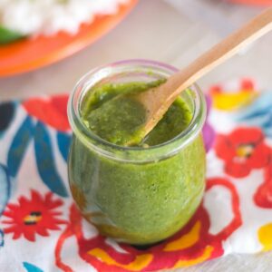 Cilantro Green Chile Lime Sauce in a small glass jar with a spoon.