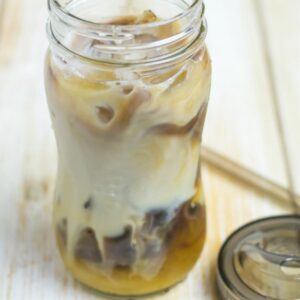 Glass jar filled with cold brewed iced coffee and cream.