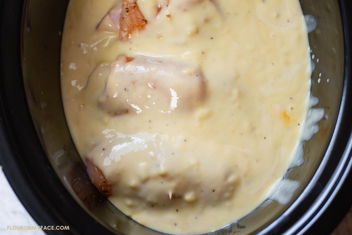 Chicken rolls covered with cream of mushroom soup in a crock pot.