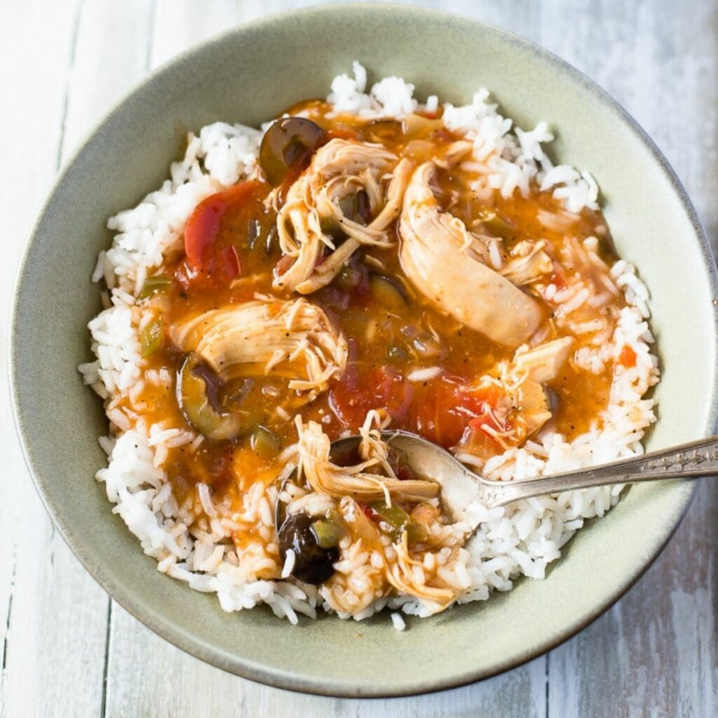 Crock pot Creole Chicken served over white rice in a bowl.