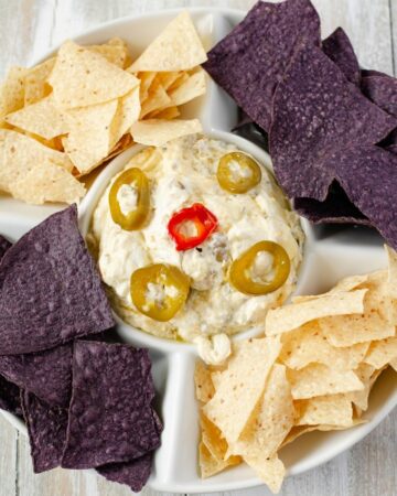 A dip bowl filled with jalapeno popper dip and chips.