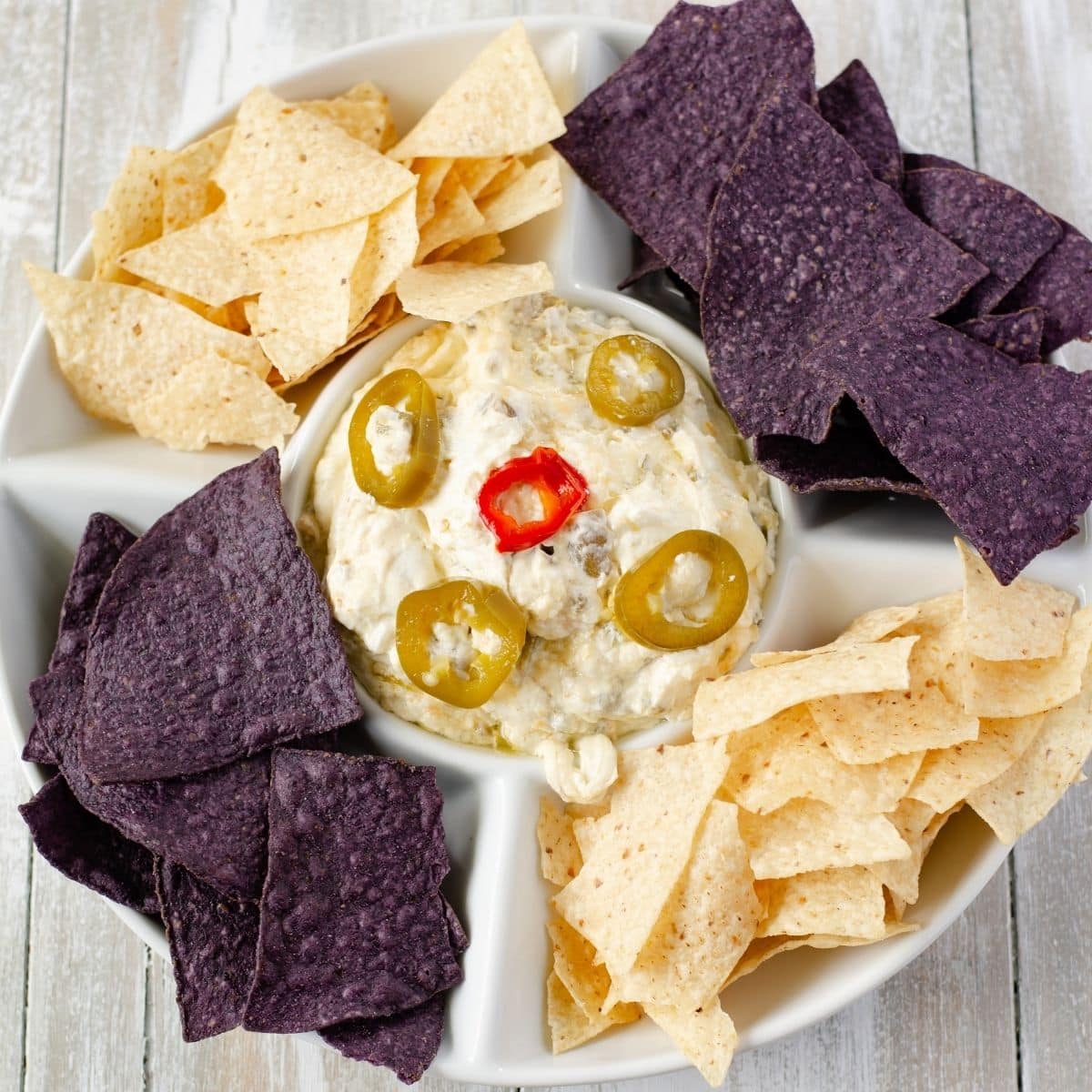 A dip bowl filled with jalapeno popper dip and chips.