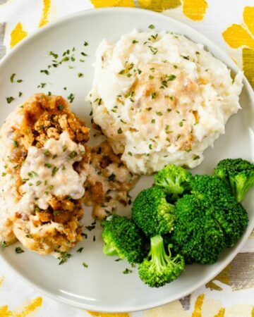 Swiss chicken served with potatoes and broccoli on a dinner plate.