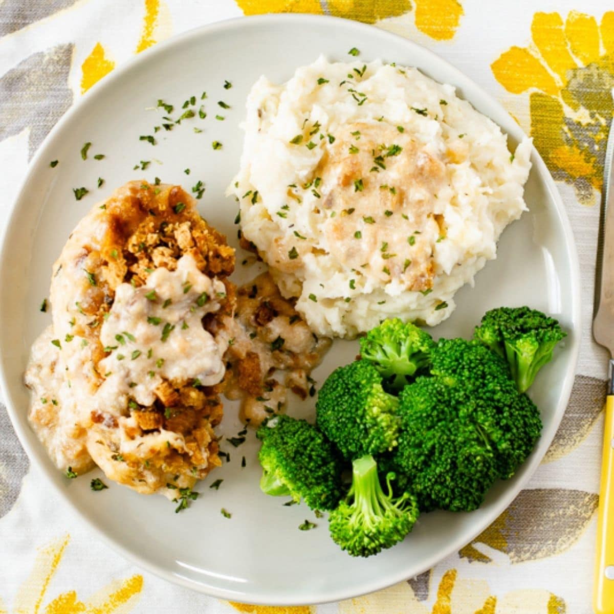Swiss chicken served with potatoes and broccoli on a dinner plate.
