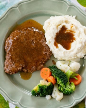 Crock Pot Cube Steak served with mashed potatoes and vegetables.