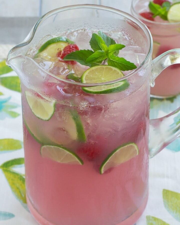 A glass pitcher full of pink lemonade.