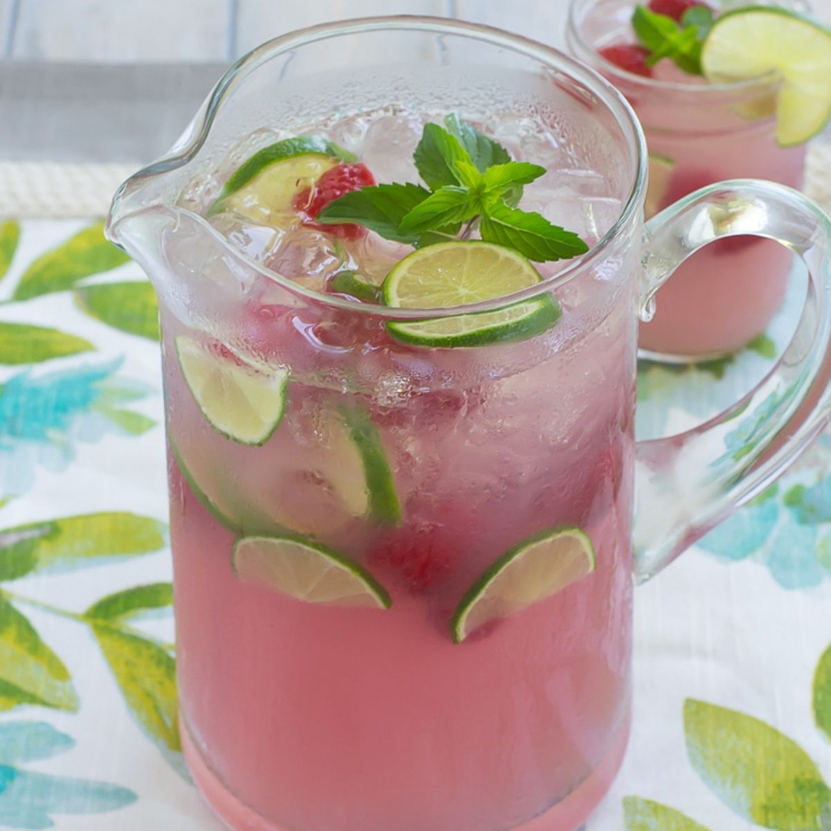 A glass pitcher full of pink lemonade.