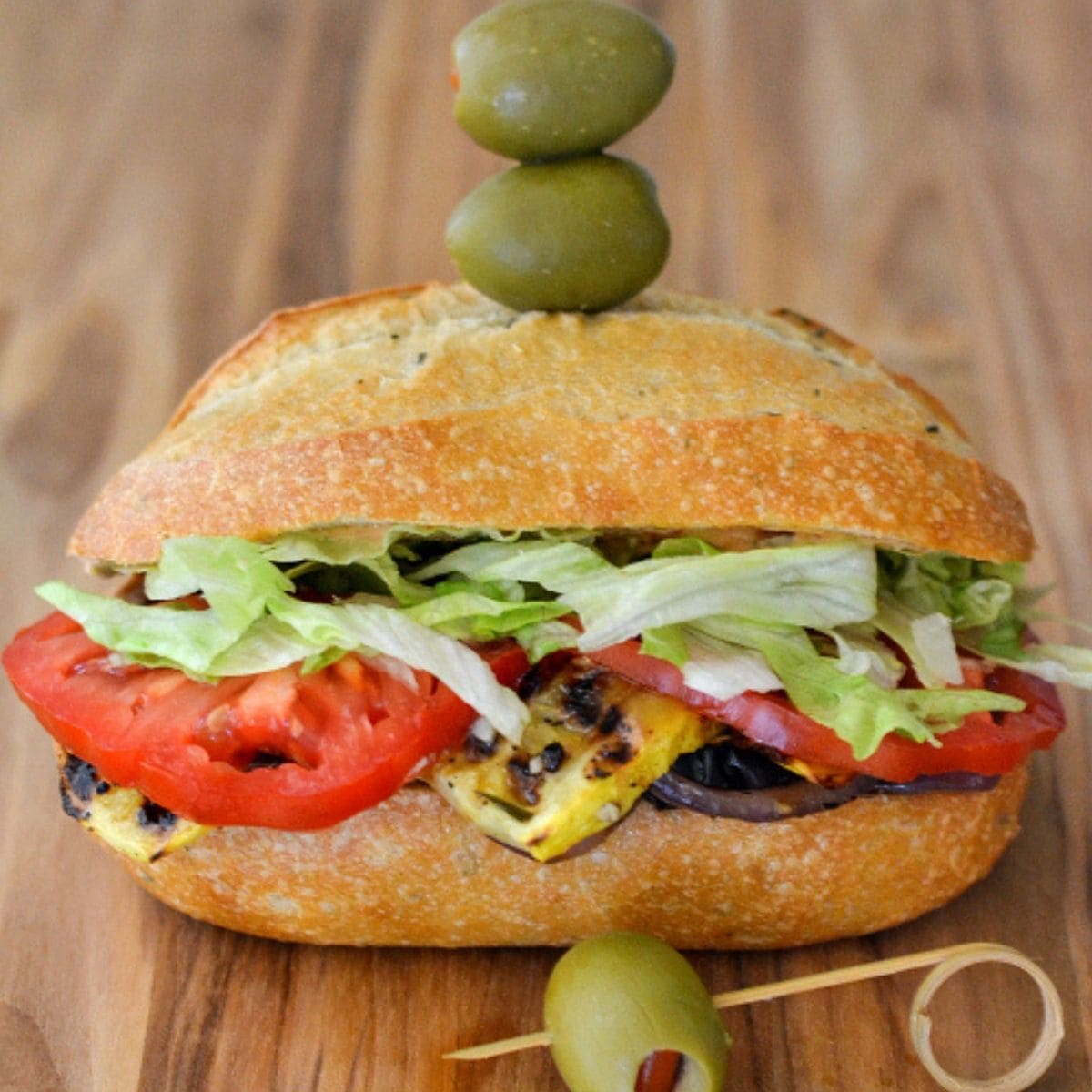 Grilled Vegetable Sandwich with olives on a cutting board.