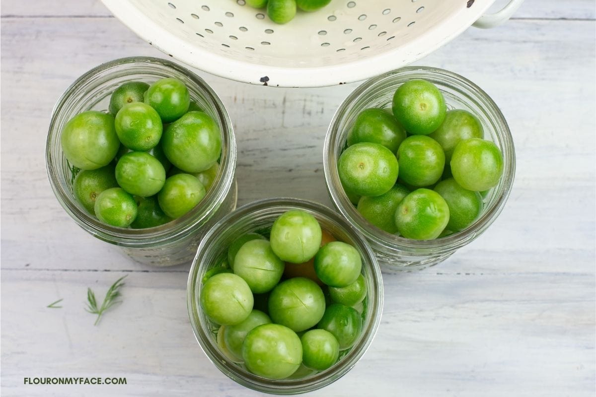 Canning jars packed with green cherry tomatoes.