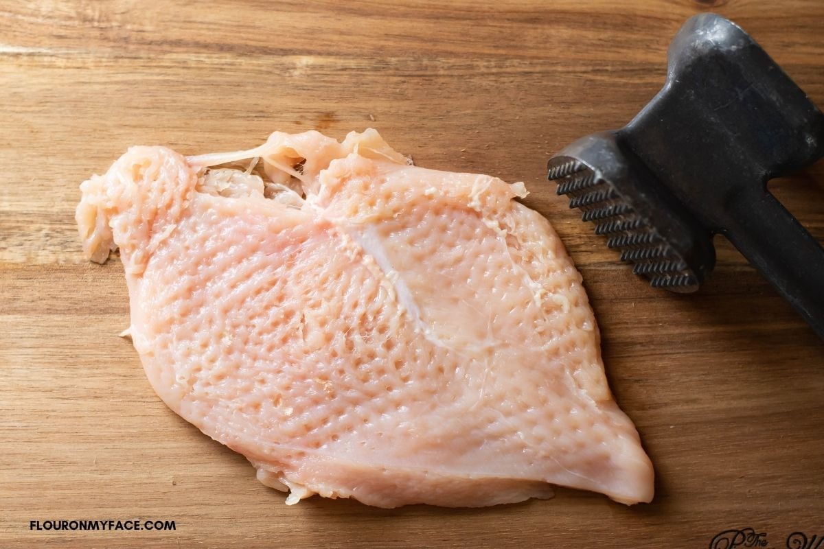A flat and pounded chicken breast on a cutting board.