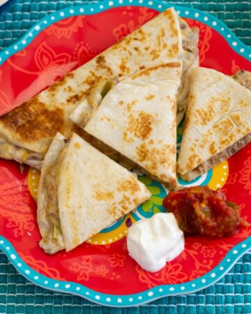 Shredded Beef Quesadillas with salsa and sour cream on a plate.