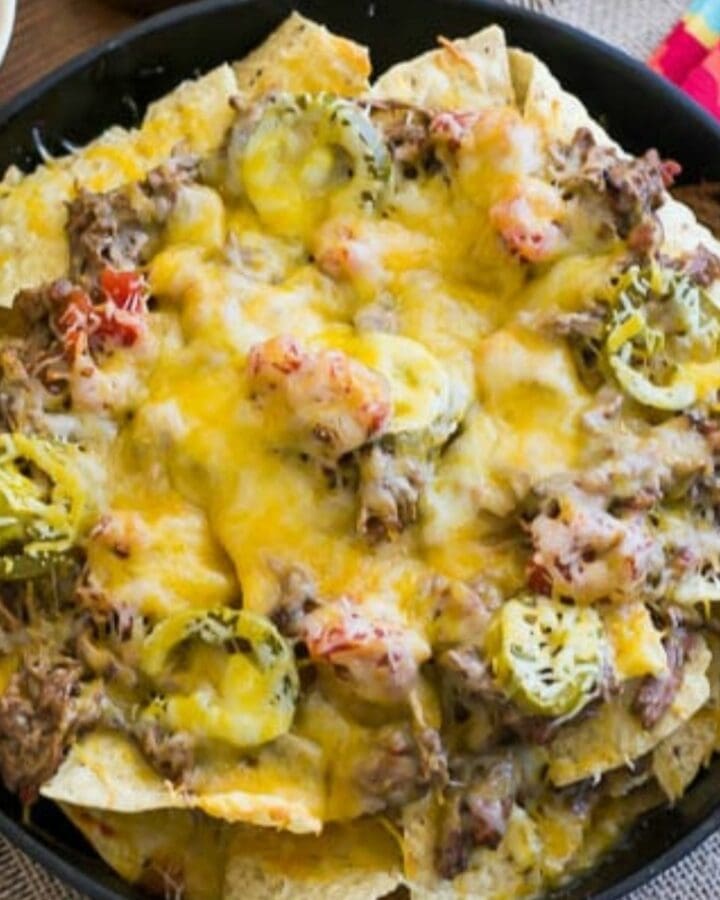 Shredded Beef Nachos cooked in a cast iron skillet with all the toppings.