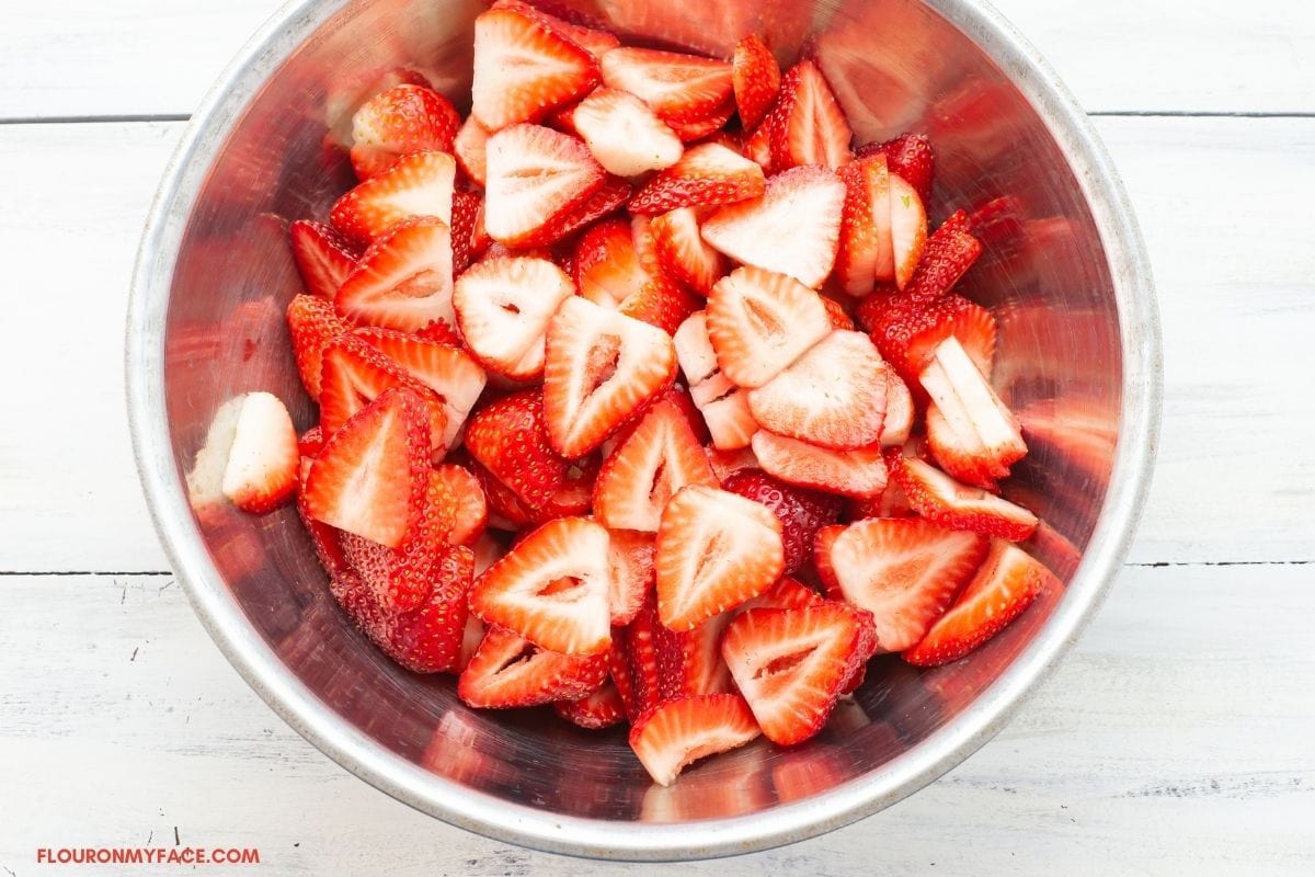 Sliced strawberries in a metal bowl.