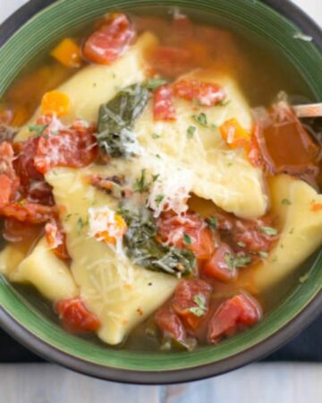 Spinach Ravioli Soup in a green bowl.