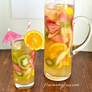 A glass and tall pitcher filled with White Moscato Sangria.
