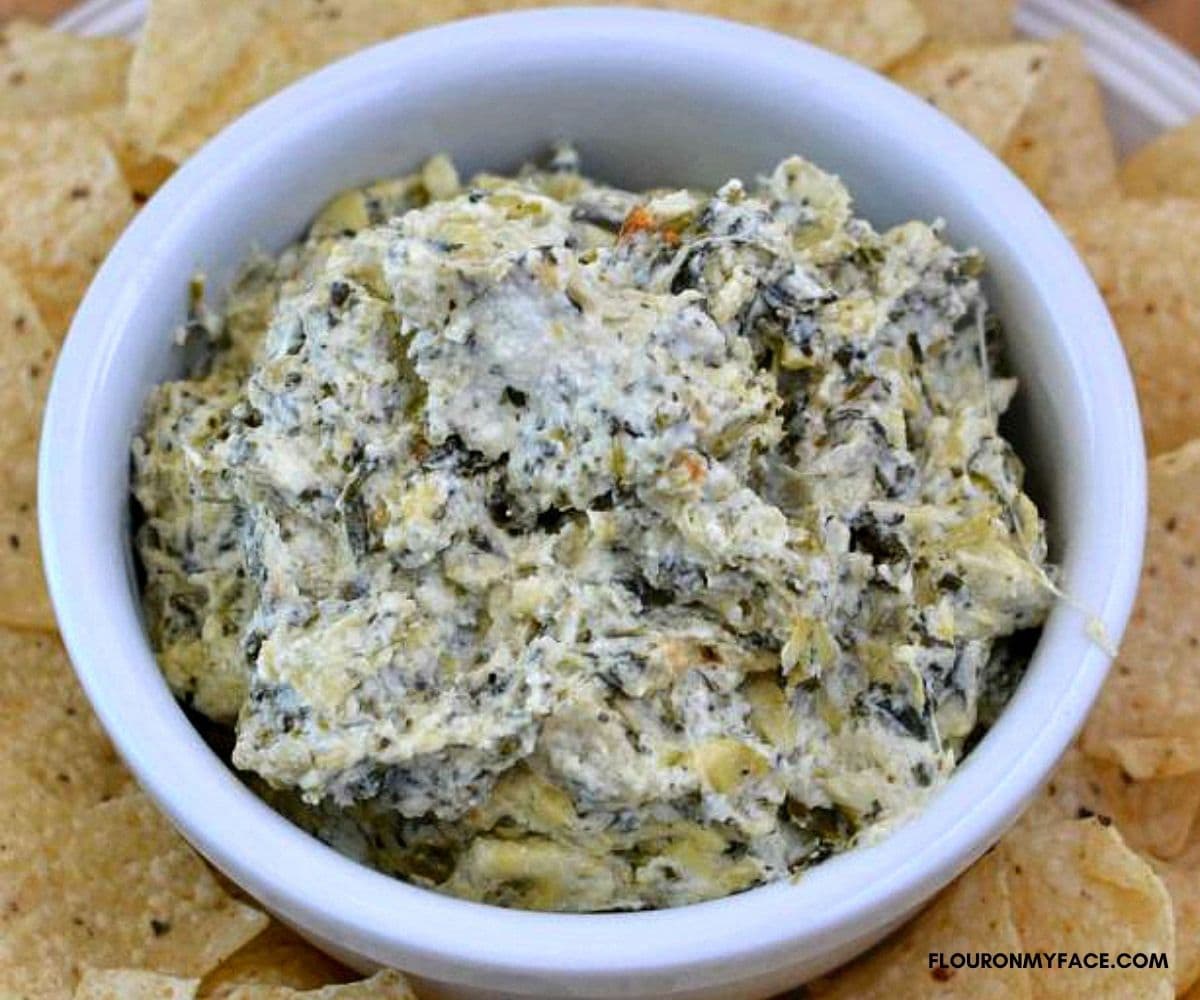 A white dip bowl filled with artichoke spinach dip.