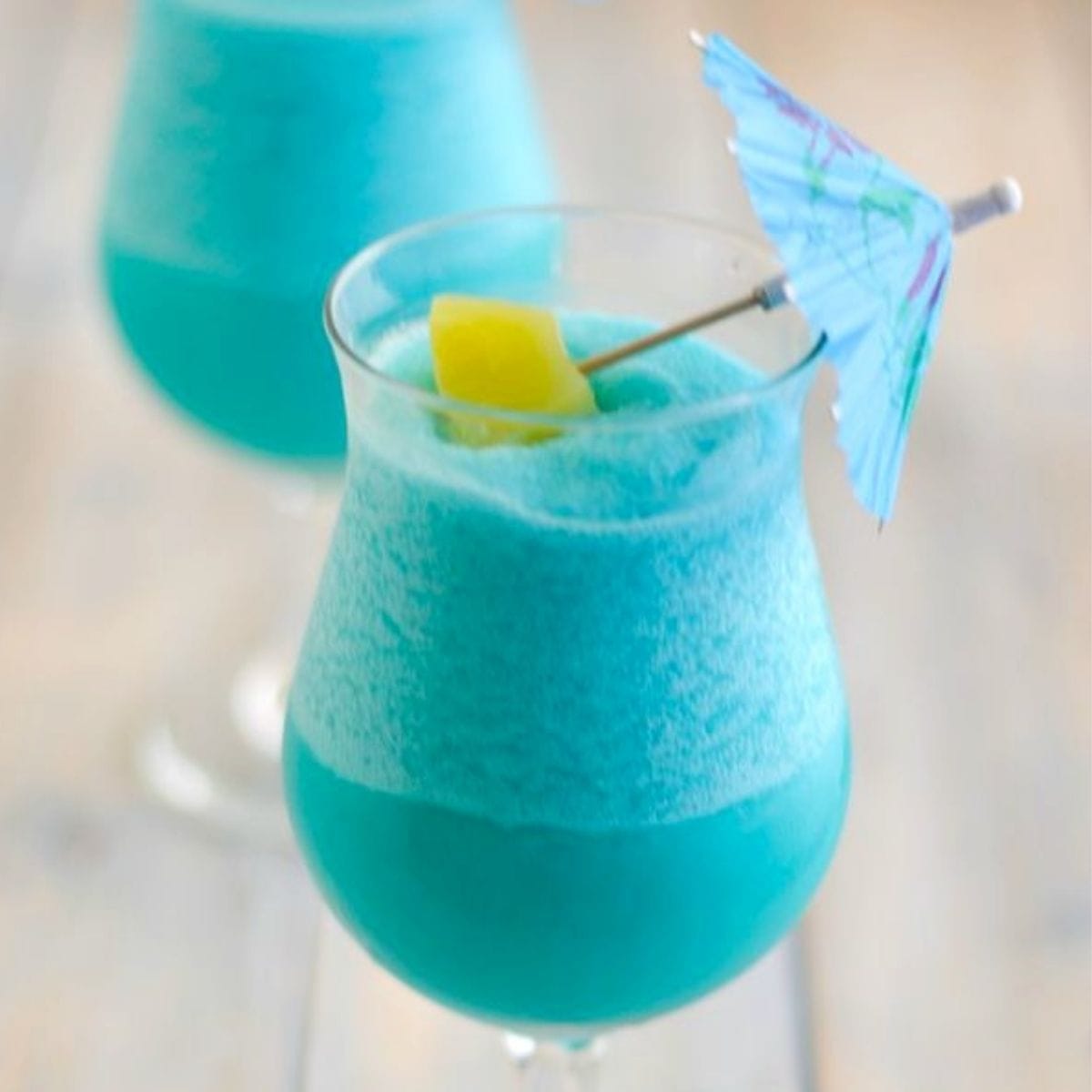 Blue Hawaiian Cocktail in a hurricane glass garnished with pineapple and umbrella.