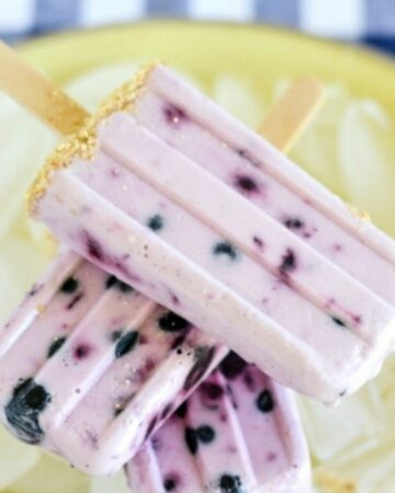 Blueberry Cheesecake Ice Pops stacked on a bed of ice.