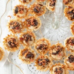 Caramelized Onion Bacon Cheesecake Bites appetizer on a glass serving tray.