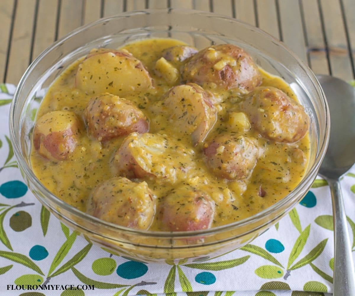 A glass serving bowl filled with cheesy ranch potatoes.