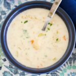 A blue bowl filled with crock pot cheesy cauliflower soup.
