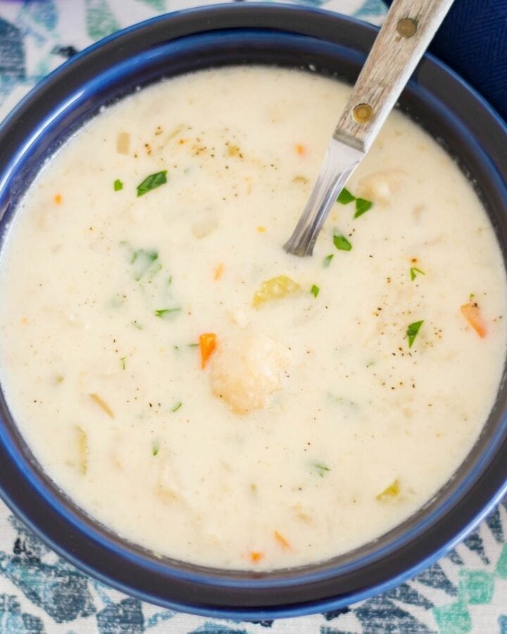 A blue bowl filled with crock pot cheesy cauliflower soup.