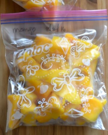 Cubed mango pieces in a freezer bag on a cutting board.