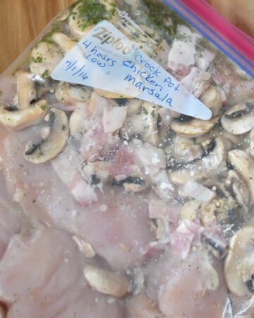 Boneless chicken, sliced mushrooms and other ingredients for chicken Marsala freeze meal.