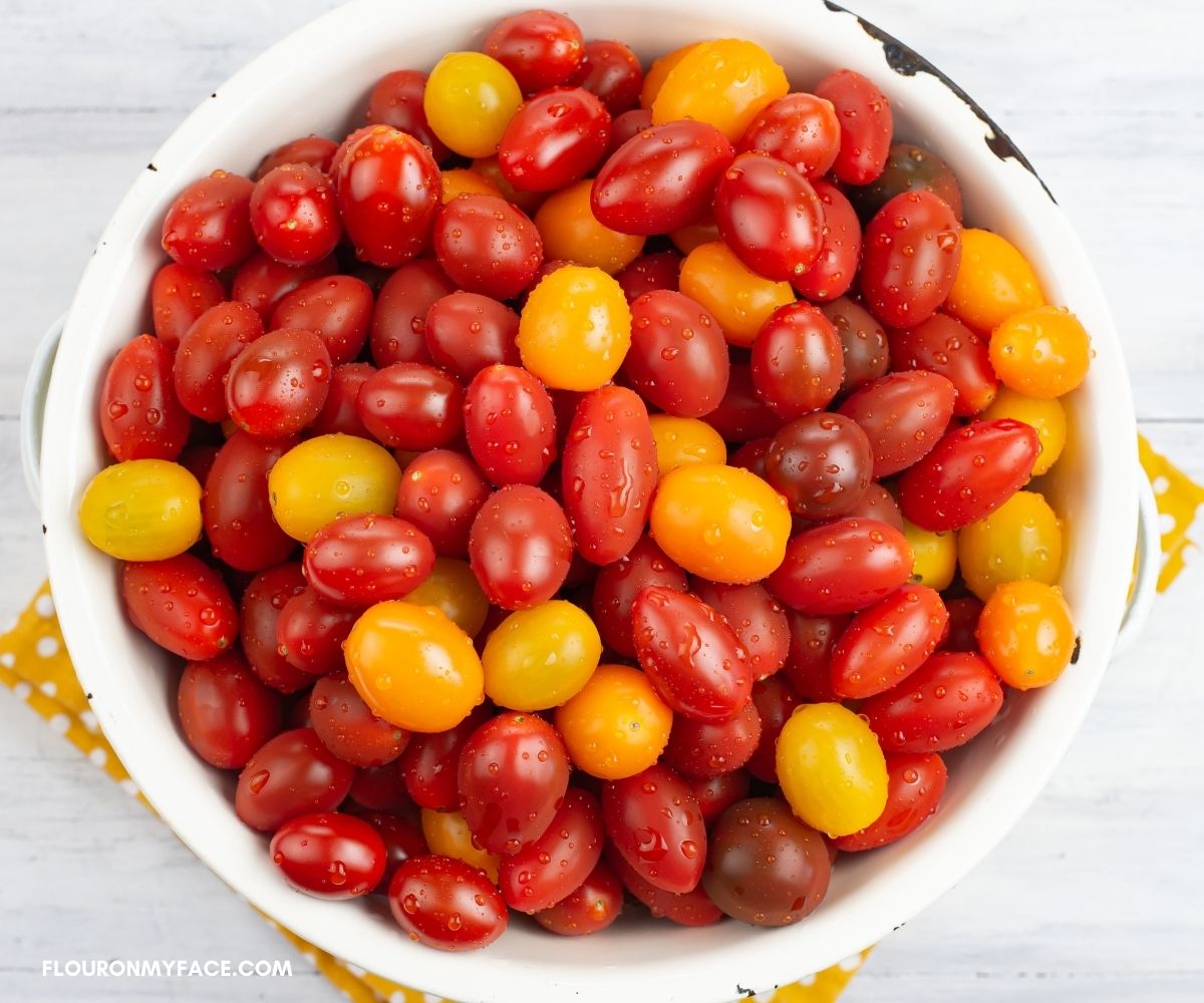 Heirloom grape tomatoes in a white colander.