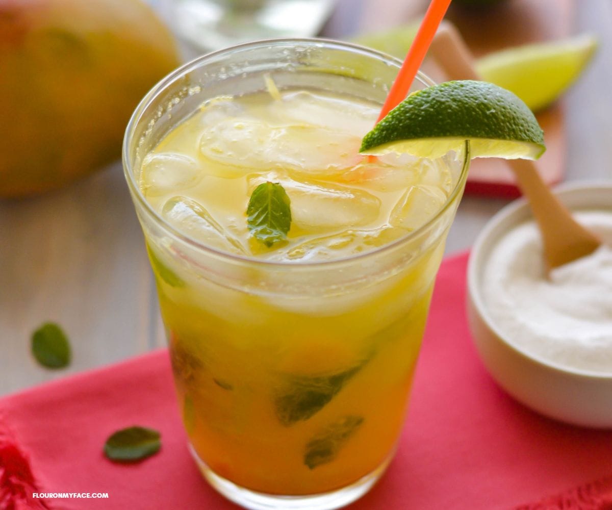 A cocktail glass filled with Mango Mojito with lime and mint garnish.