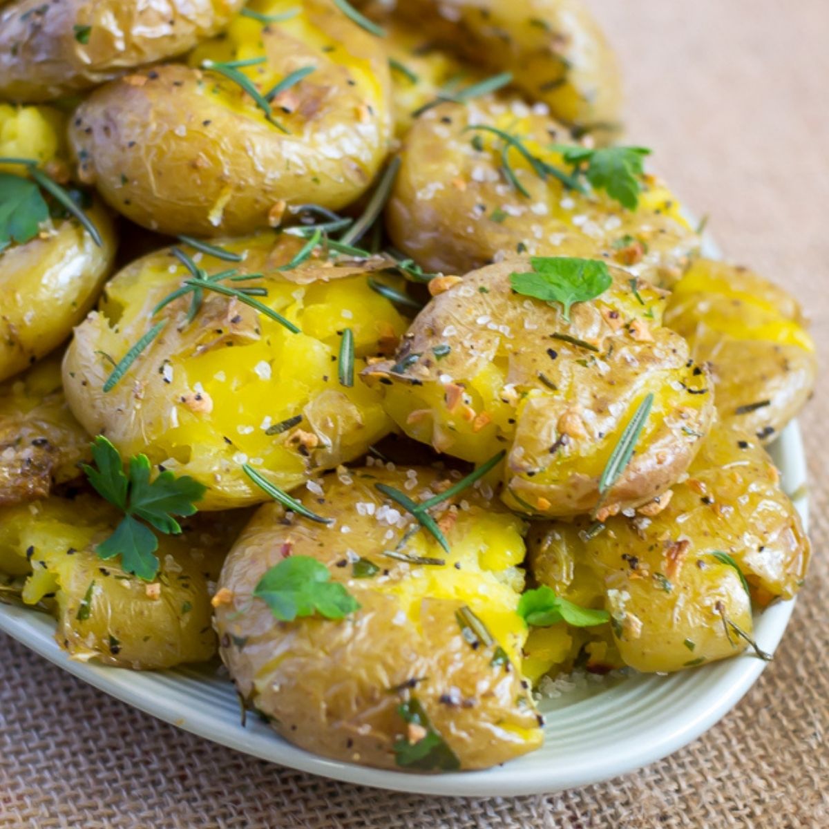A pile of garlic rosemary smashed potatoes on a serving platter.