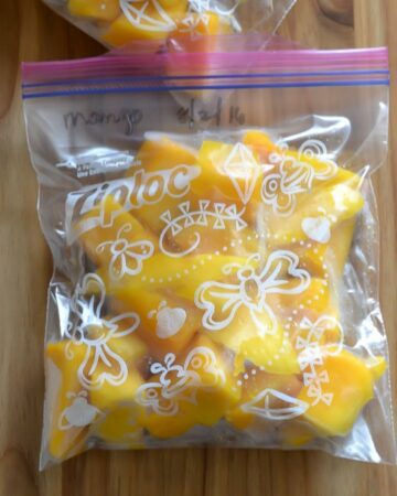 Cubed mango pieces in a freezer bag on a cutting board.