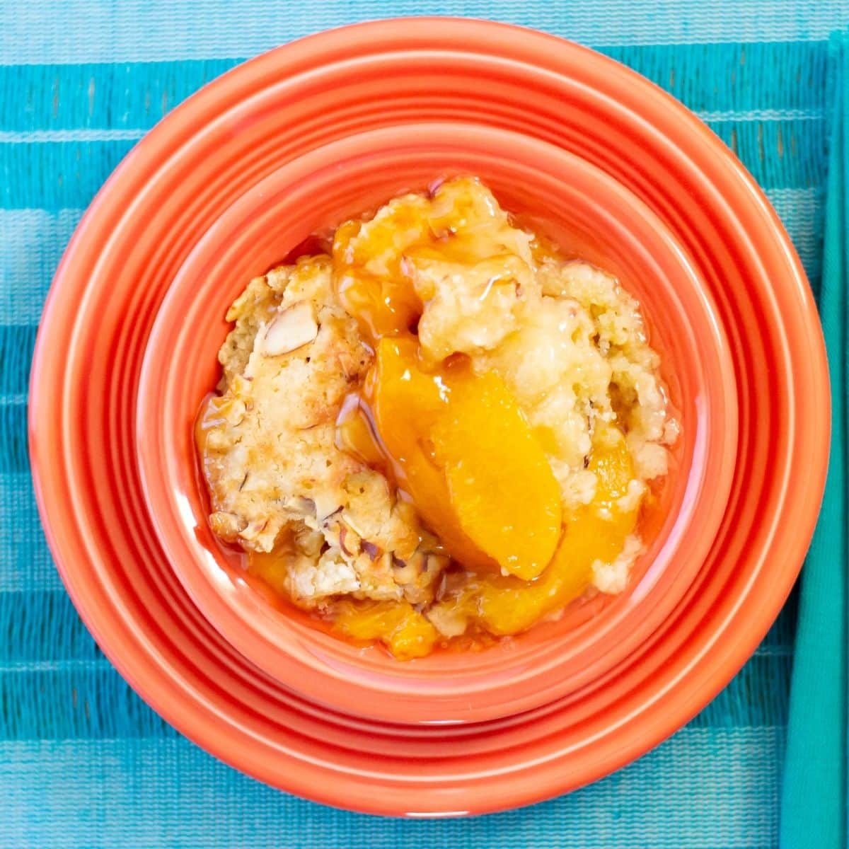 Peach cobbler in a dessert bowl on a placemat.