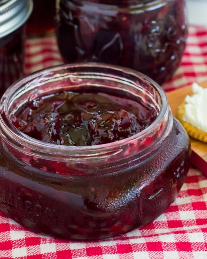 A canning jar filled with cherry habanero jam served with crackers and cream cheese.