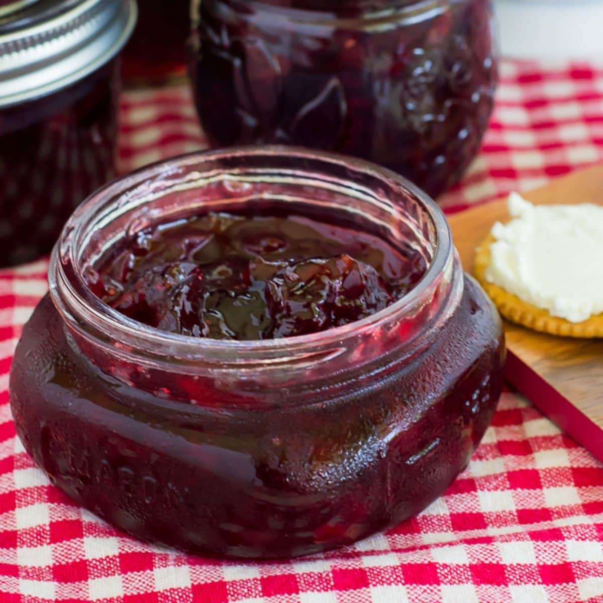 A canning jar filled with cherry habanero jam served with crackers and cream cheese.