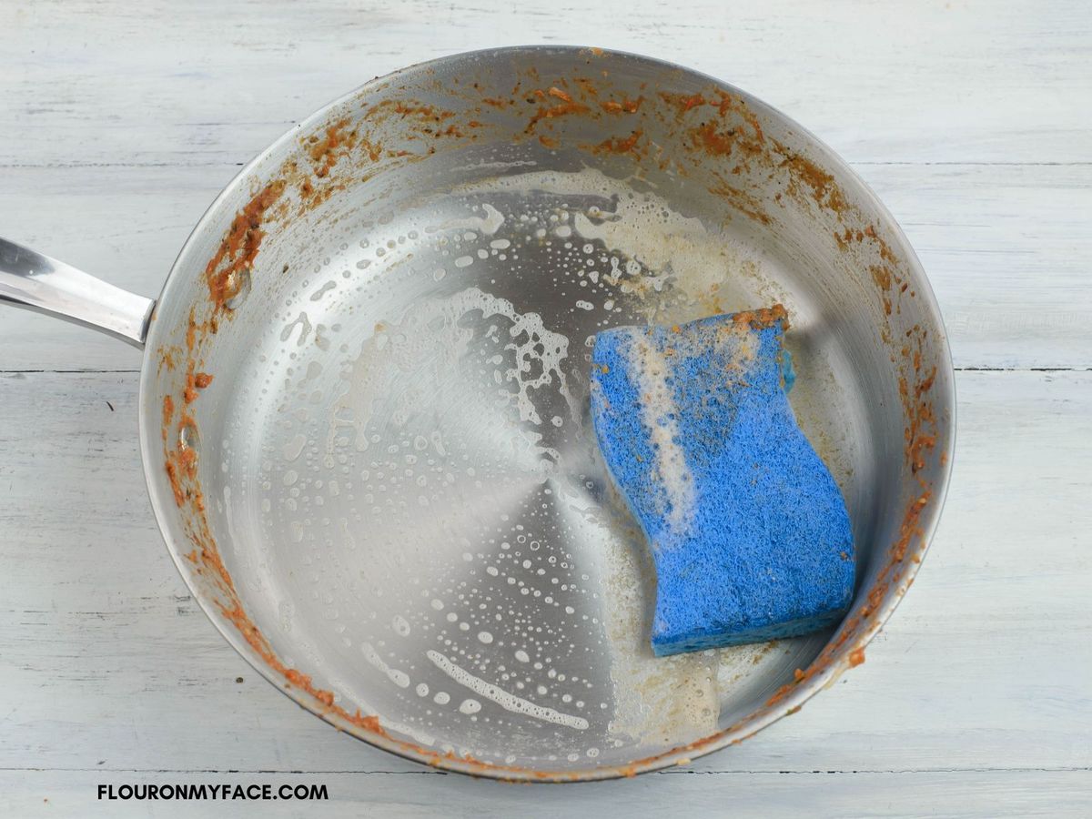 Cleaning a non stick skillet with sponge and soap.