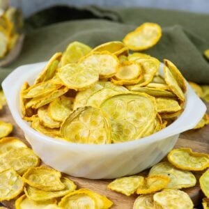 Dehydrated yellow squash chips in a white glass bowl.