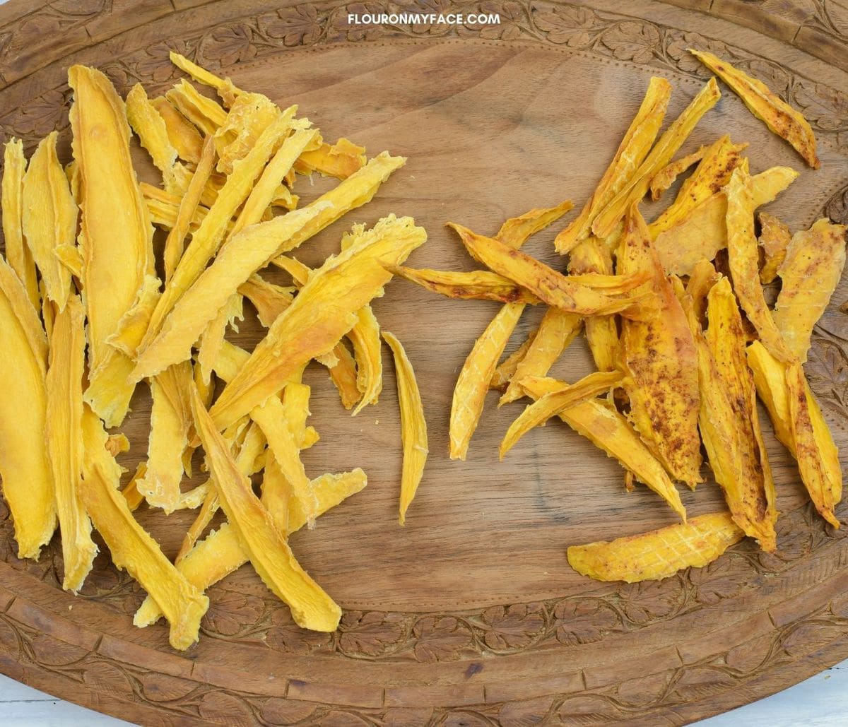 Dried mango pieces on a wooden serving tray.