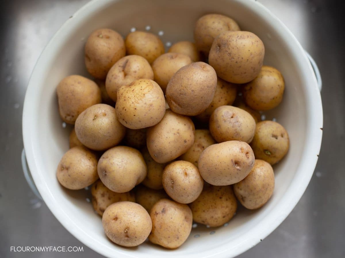 A colander filled with new baby potatoes in the sink.