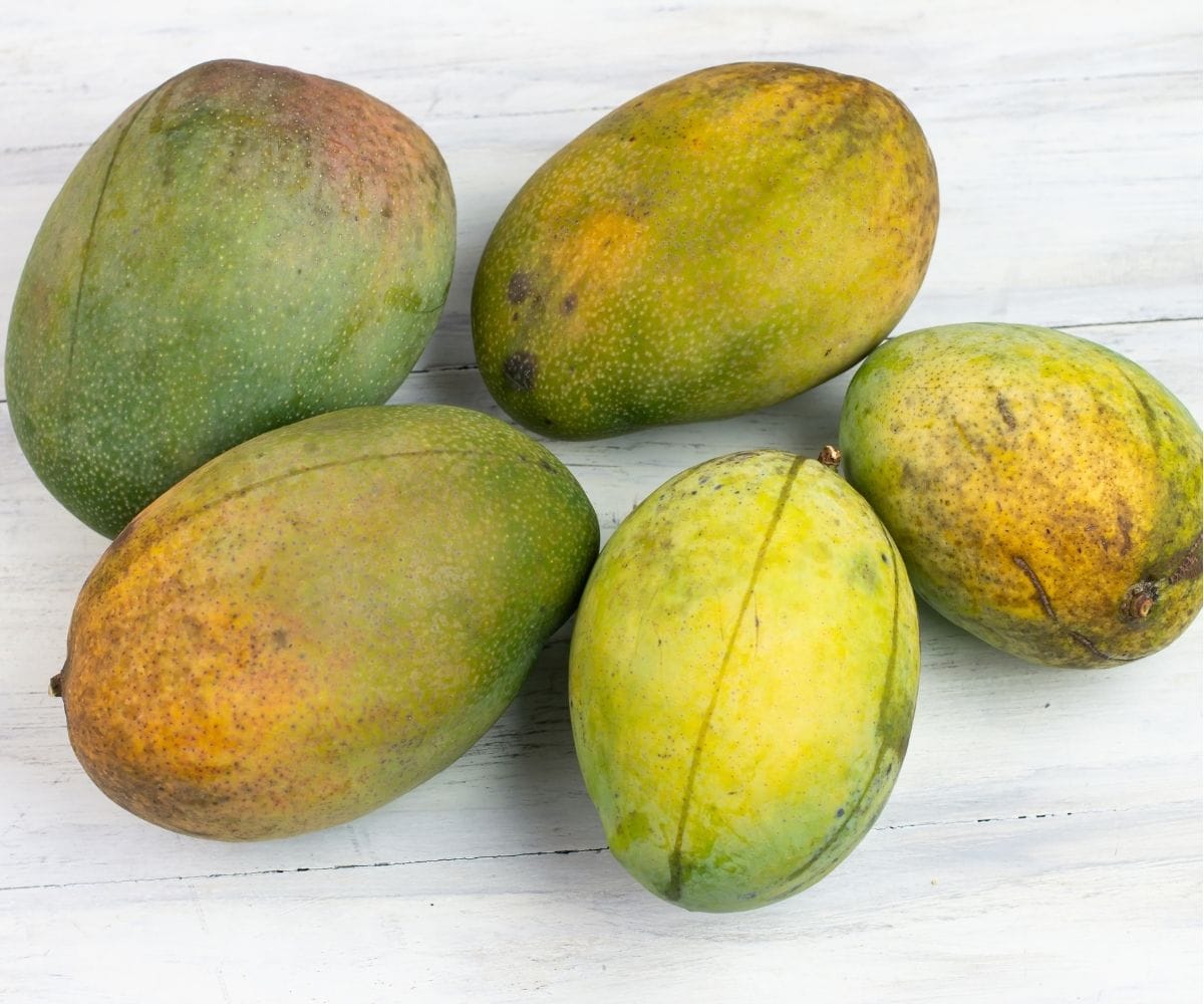 5 Fresh mangos on a table top.