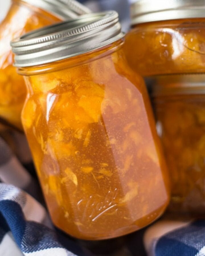 A basket filled with jars of homemade peach preserves.